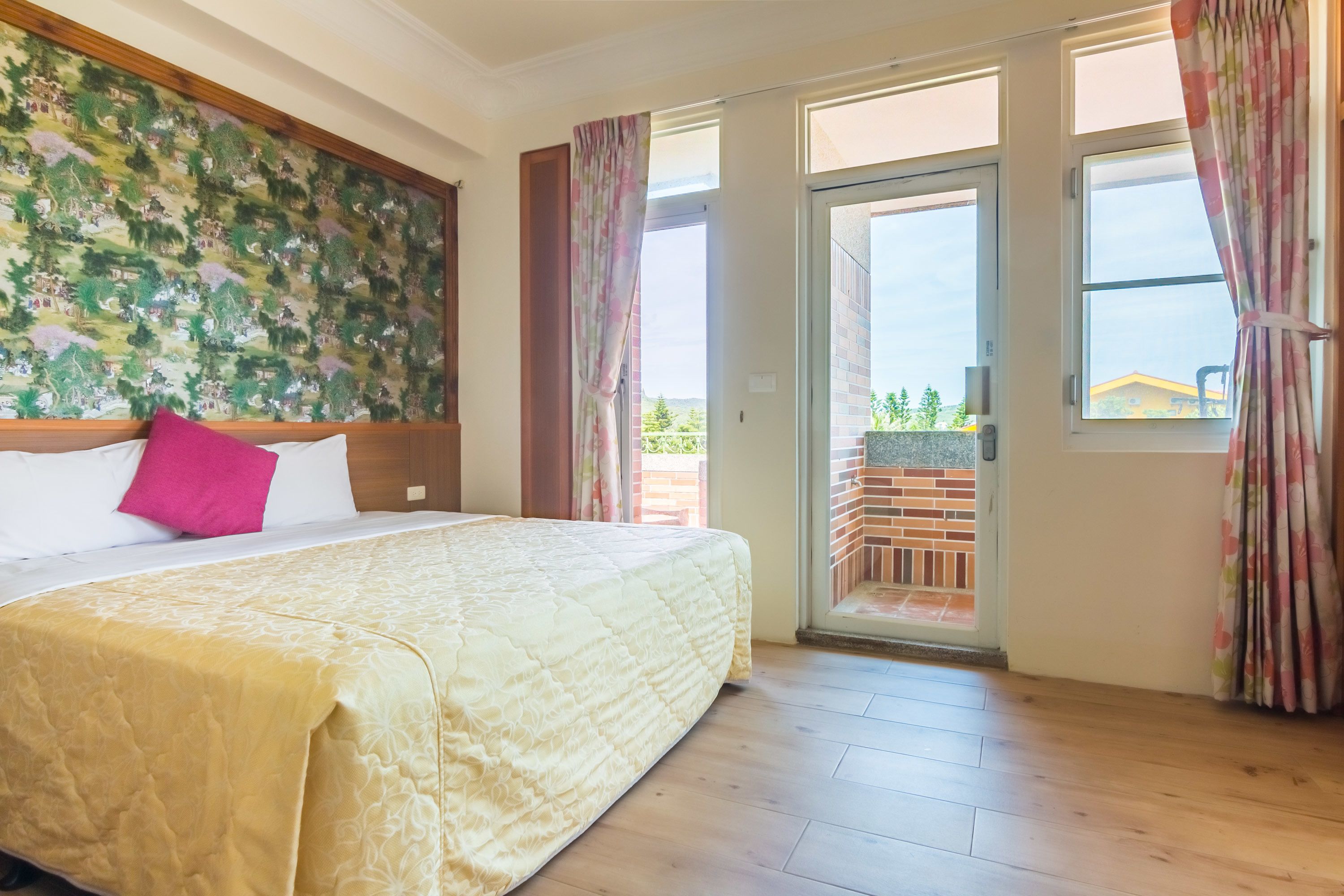 Una habitación de hotel con una cama grande, un balcón con vistas y piso de madera.