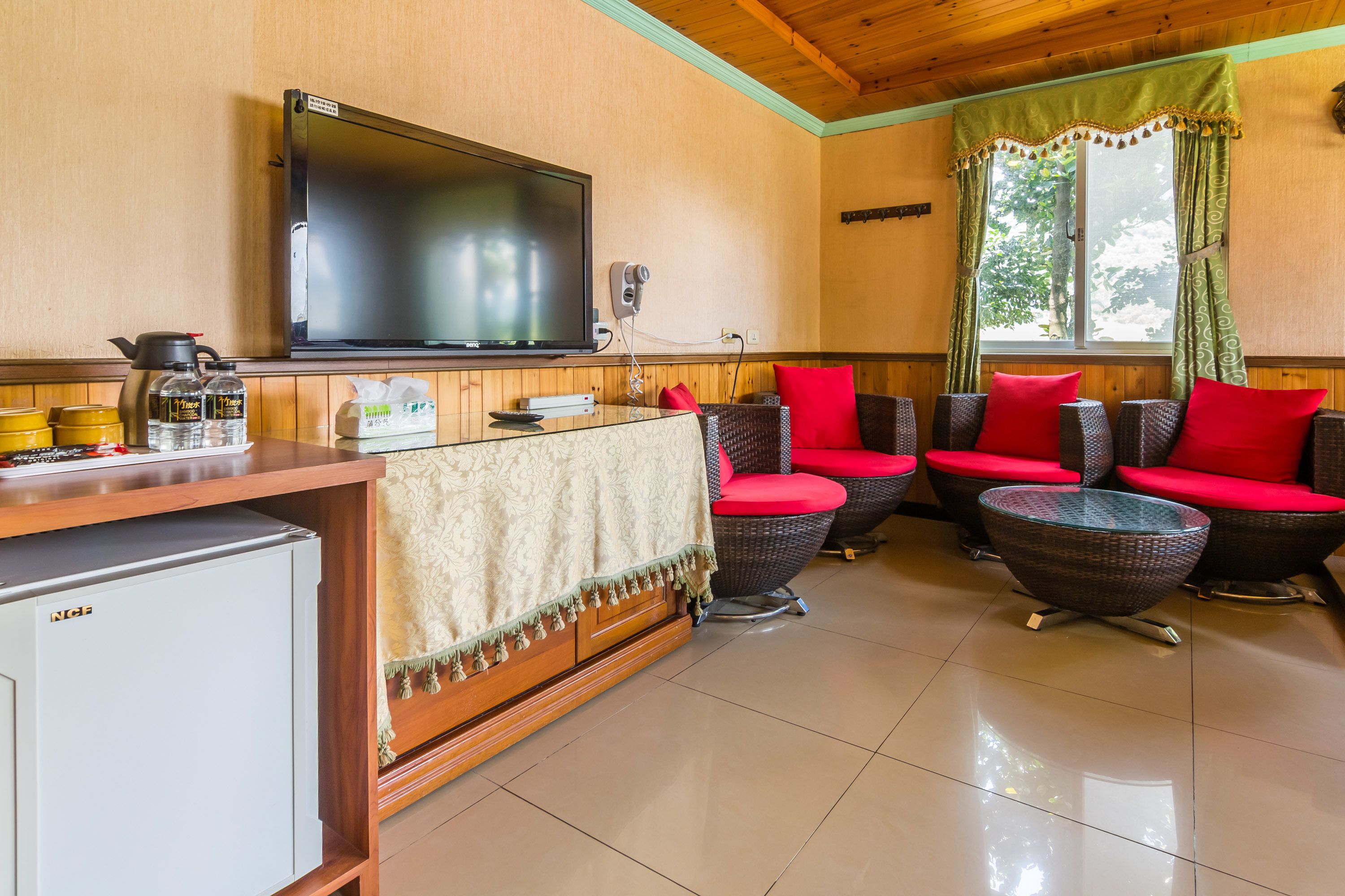 A living room with a TV, seating area, and a small fridge.
