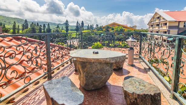 A terrace with a stone table and benches, surrounded by a wrought iron railing, overlooking a green landscape and buildings. - Kenting Maya House B&B (Hengchun)