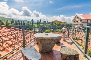 A terrace with a stone table and benches, surrounded by a wrought iron railing, overlooking a green landscape and buildings. - Kenting Maya House B&B (Hengchun)