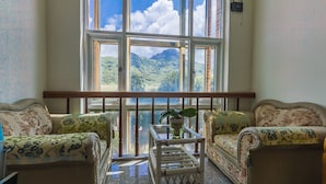 A room with two sofas facing a large window overlooking a mountainous landscape. - Kenting Maya House B&B (Hengchun)