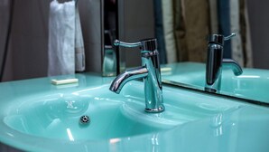 A bathroom with a glass sink, chrome faucets, and a mirror. - The Father's Hotel (Accra)