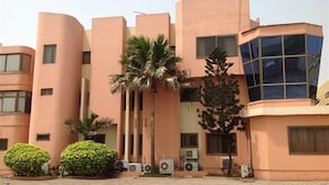 A building with a modern architectural style, featuring curved and angular structures. There are several air conditioning units mounted on the exterior walls. - The Father's Hotel (Accra)