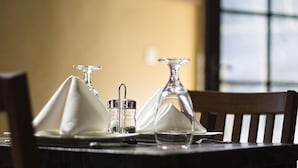 A dining table set with a white napkin, two glass salt and pepper shakers, and a wine glass. - The Father's Hotel (Accra)