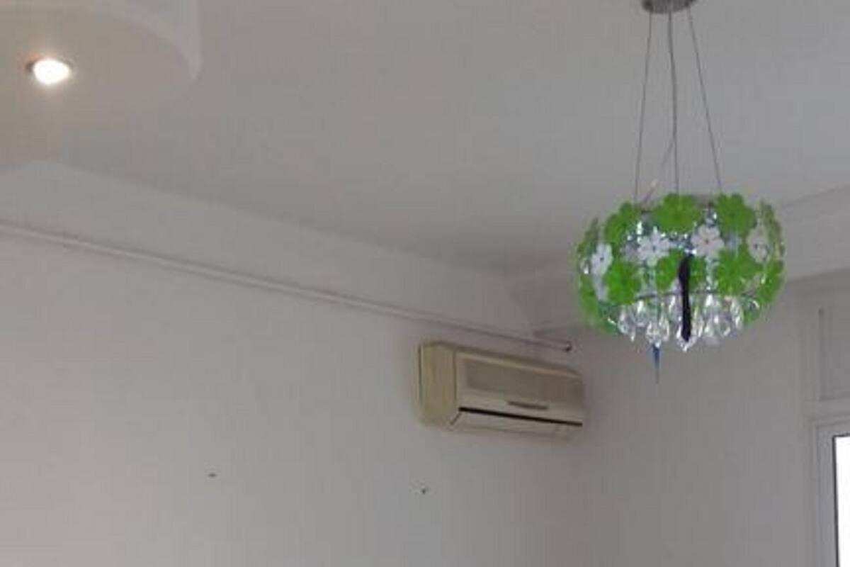A modern living room with a green sofa, a small table with a book and glasses, and a ceiling light fixture.
