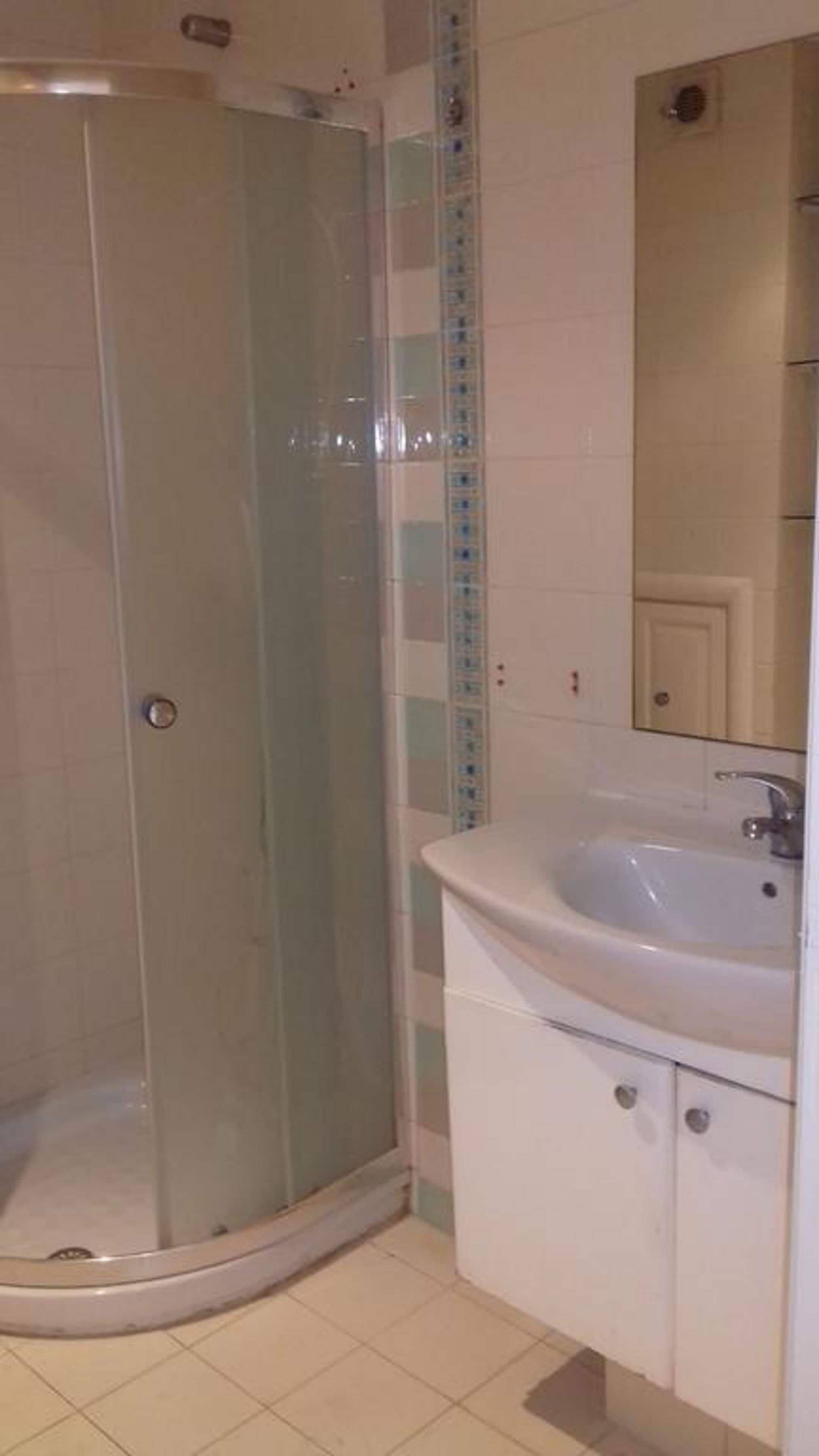 Une salle de bain avec une douche à parois de verre, un lavabo blanc et un miroir au-dessus du lavabo.
