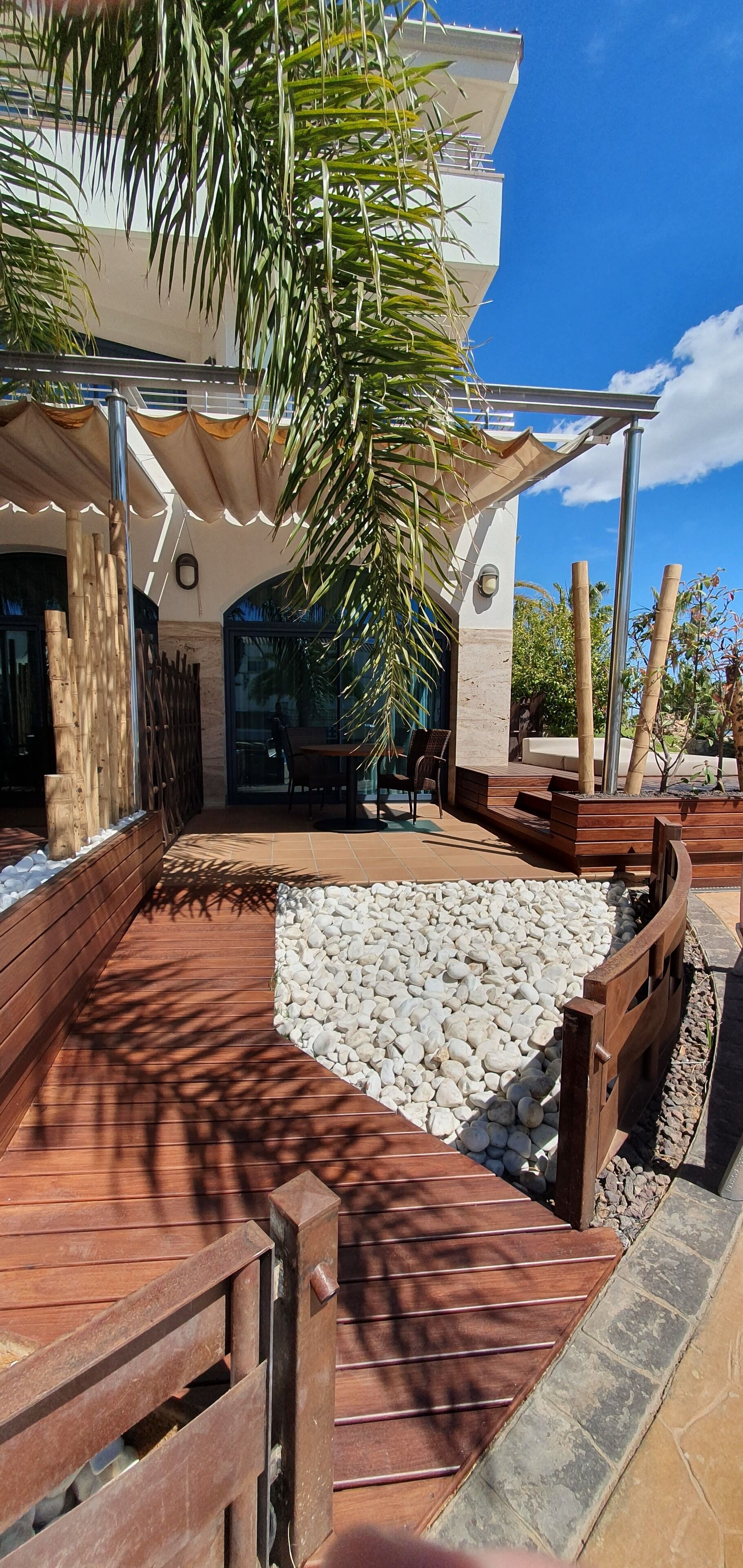 A modern outdoor area with a wooden deck, a seating area, and a water feature.