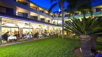 Hotel con comedor al aire libre, varios balcones y césped bien cuidado.