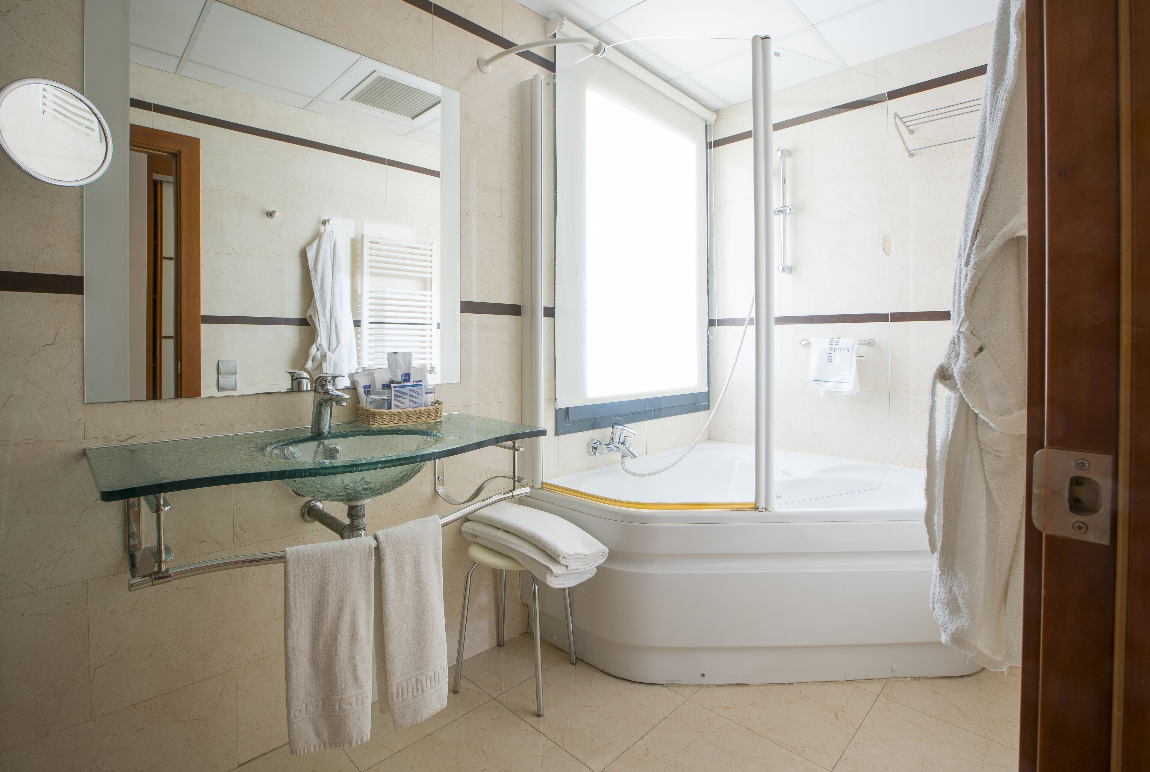 A modern bathroom with a glass sink, a bathtub, and a shower.