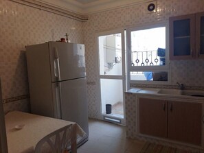 A kitchen with a refrigerator, sink, and cabinets. - Benzineb Immo Menzeh (Ariana)