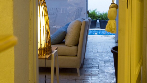A narrow hallway with a sofa and a lamp, leading to a room with a view of the sky. - Dar Indigo (Sidi Bou Said)