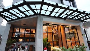 Un bâtiment moderne doté d’une entrée couverte, de grandes fenêtres et de vélos garés à l’extérieur.