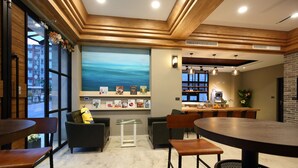 Un café moderne avec des poutres en bois au plafond, une grande fenêtre offrant une belle vue et différents types de sièges, notamment des tables et des chaises.