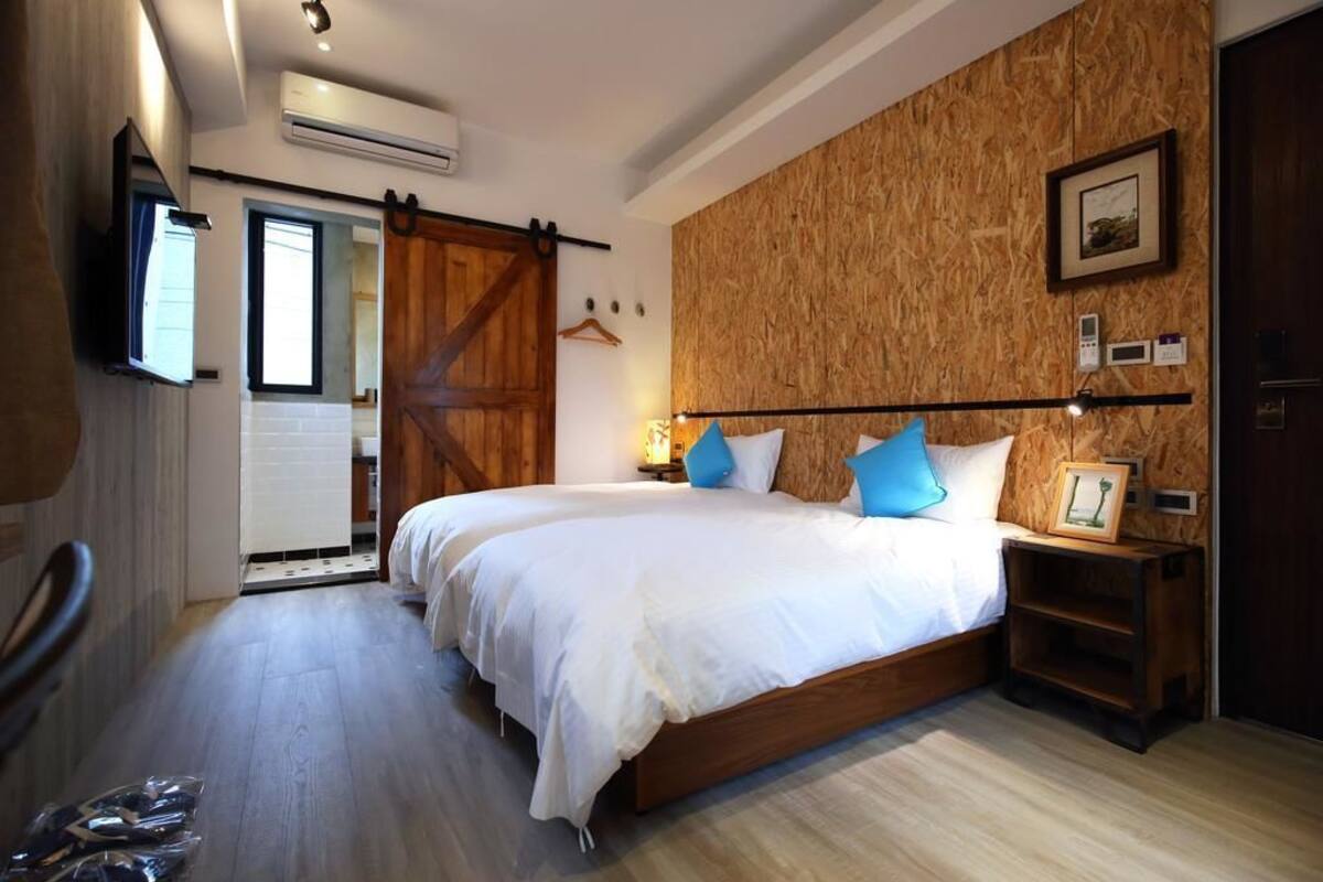 Un dormitorio con una cama grande, paneles de madera en la pared, un televisor montado y una puerta corredera.