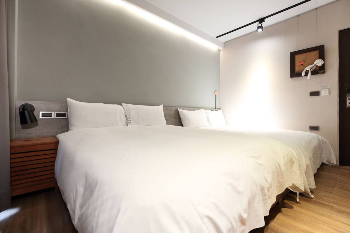 Una habitación de hotel moderna con una cama grande, una mesita de noche de madera y una lámpara de pared.