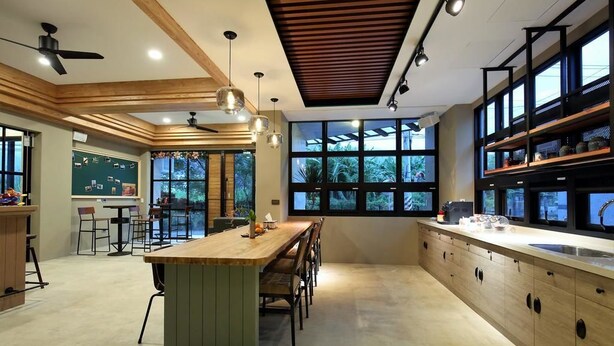 Une cuisine moderne dotée d’un îlot central, de meubles en bois et d’une grande fenêtre offrant une vue sur la verdure.