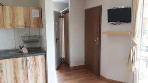 Una cocina con armarios de madera, un lavamanos y un televisor montado en la pared.