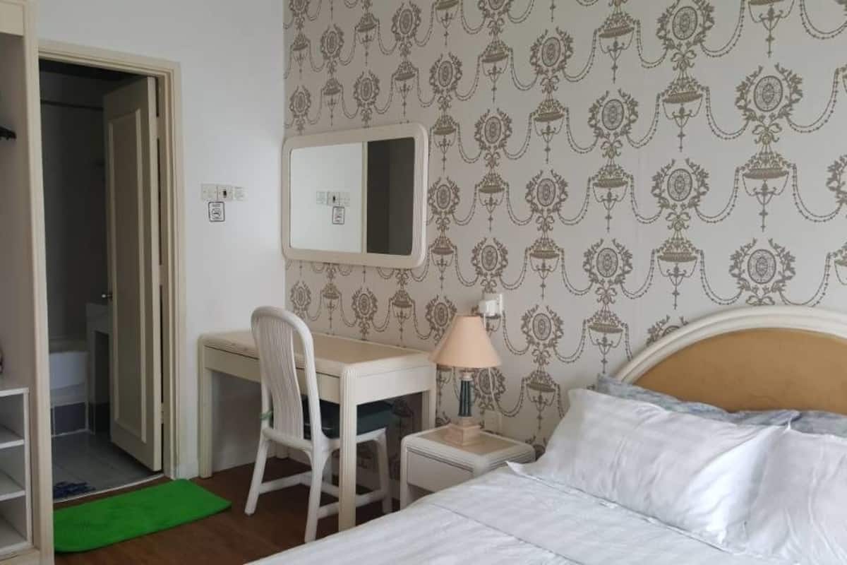 A bedroom with a bed, a desk, a chair, a mirror, and a wardrobe.