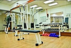 A gym with various exercise equipment, including a bench, weight machines, and dumbbells.