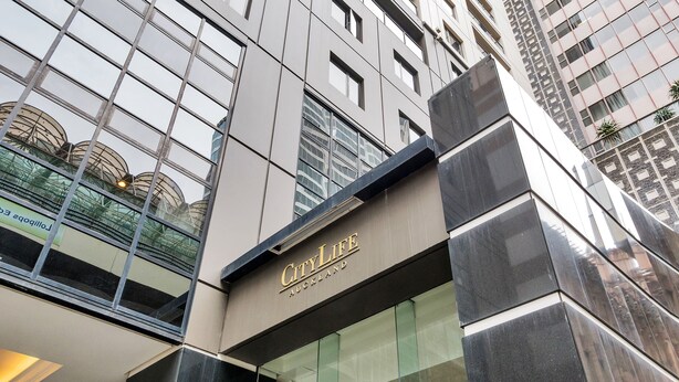 Un edificio moderno con fachada de vidrio y el nombre "CityLife Auckland" en la parte frontal.
