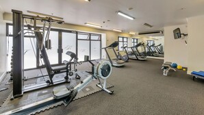 Un gimnasio con máquinas de cardio, equipo de levantamiento de pesas y colchonetas de ejercicio.
