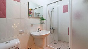 Une salle de bain avec un lavabo blanc, un miroir et une douche.