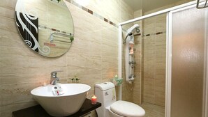 Une salle de bain dotée d’un grand lavabo ovale, de toilettes, d’un espace douche et d’un miroir avec un cadre décoratif.