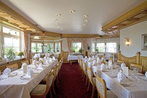 A formal dining room with multiple tables set for a meal, wooden chairs, and a red carpet. - Walserhof (Wasserburg am Bodensee)