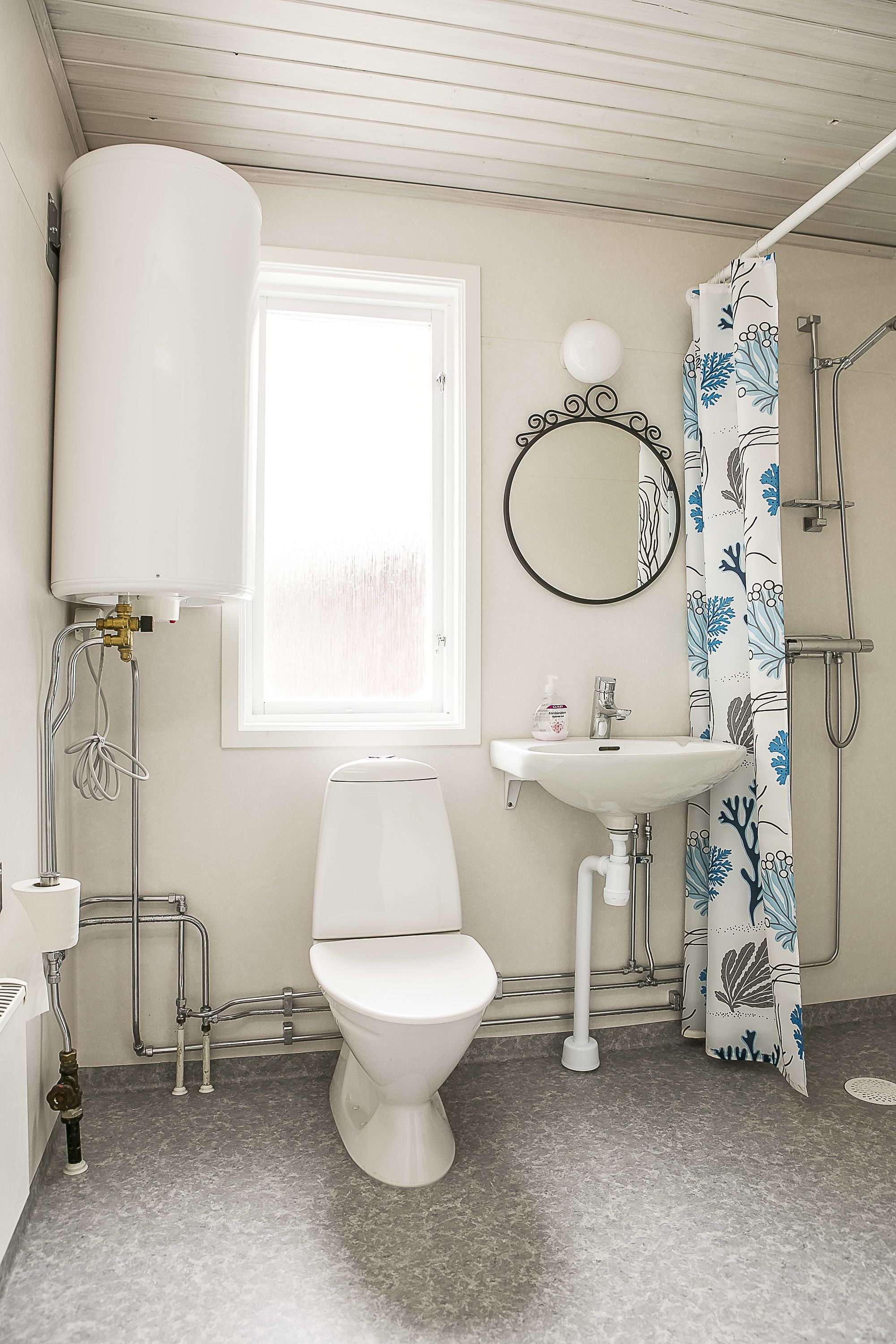 A bathroom with a toilet, sink, shower, and a window providing natural light.