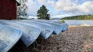 Una fila de canoas con los números 15, 16 y 17, atadas a un muelle de madera junto a un lago con un bosque al fondo.