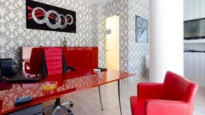 A modern office with a glass desk, red office chair, and patterned wallpaper. - Aris Apartments (Malia)