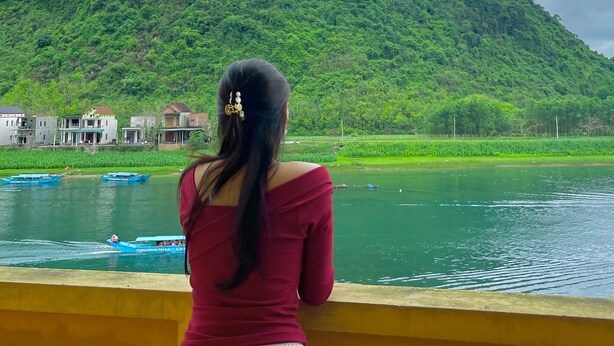 A person standing by a river with a mountain in the background. - Phong Nha River View Hotel (Phong Nha)