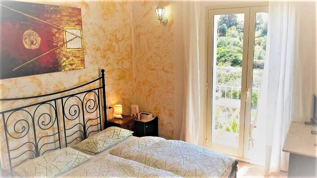 Una camera da letto con un letto, un comodino, una lampada e un quadro appeso al muro.