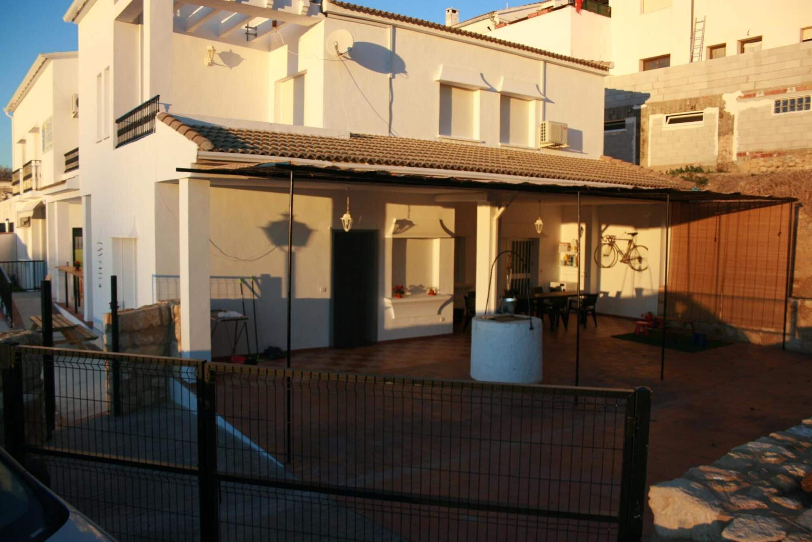 Una casa de dos pisos con techo de tejas y un patio cubierto.