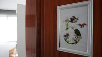 Une œuvre d’art encadrée représentant des fleurs et des coccinelles, accrochée à un mur en bois.