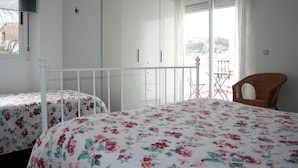 Een slaapkamer met twee bedden, een balkon en uitzicht.