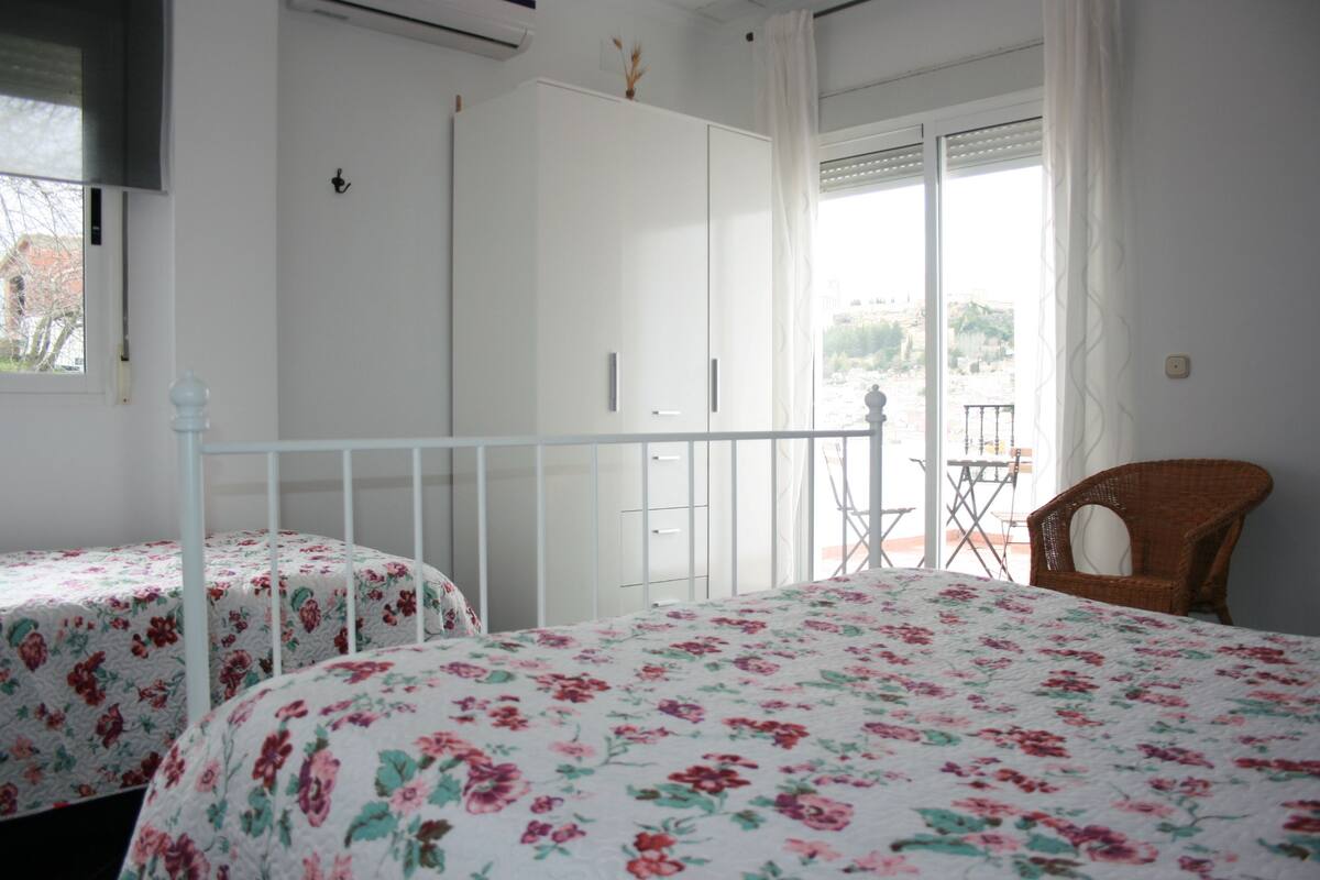 Une chambre avec deux lits, un balcon et une vue sur l’extérieur.