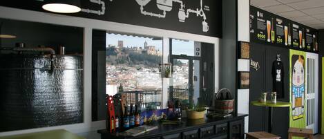 Una cocina con vistas a un paisaje urbano, una grifería de cerveza y una encimera con botellas y una planta.