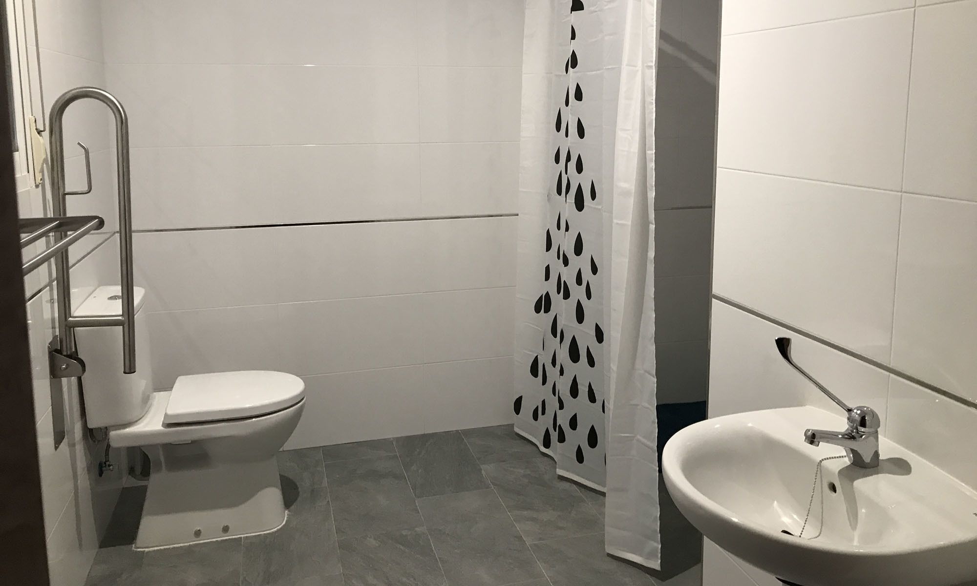 A bathroom with a toilet, a sink, and a shower curtain with a polka dot pattern.