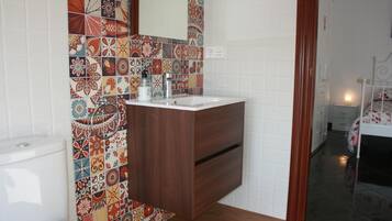 A bathroom with a wooden vanity, a white sink, and a colorful tile backsplash.
