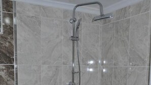 Un baño con ducha, paredes de azulejos y un inodoro.