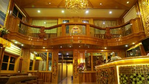 Un vestíbulo imponente con candelabro, detalles de madera ornamentados y un mostrador de recepción.