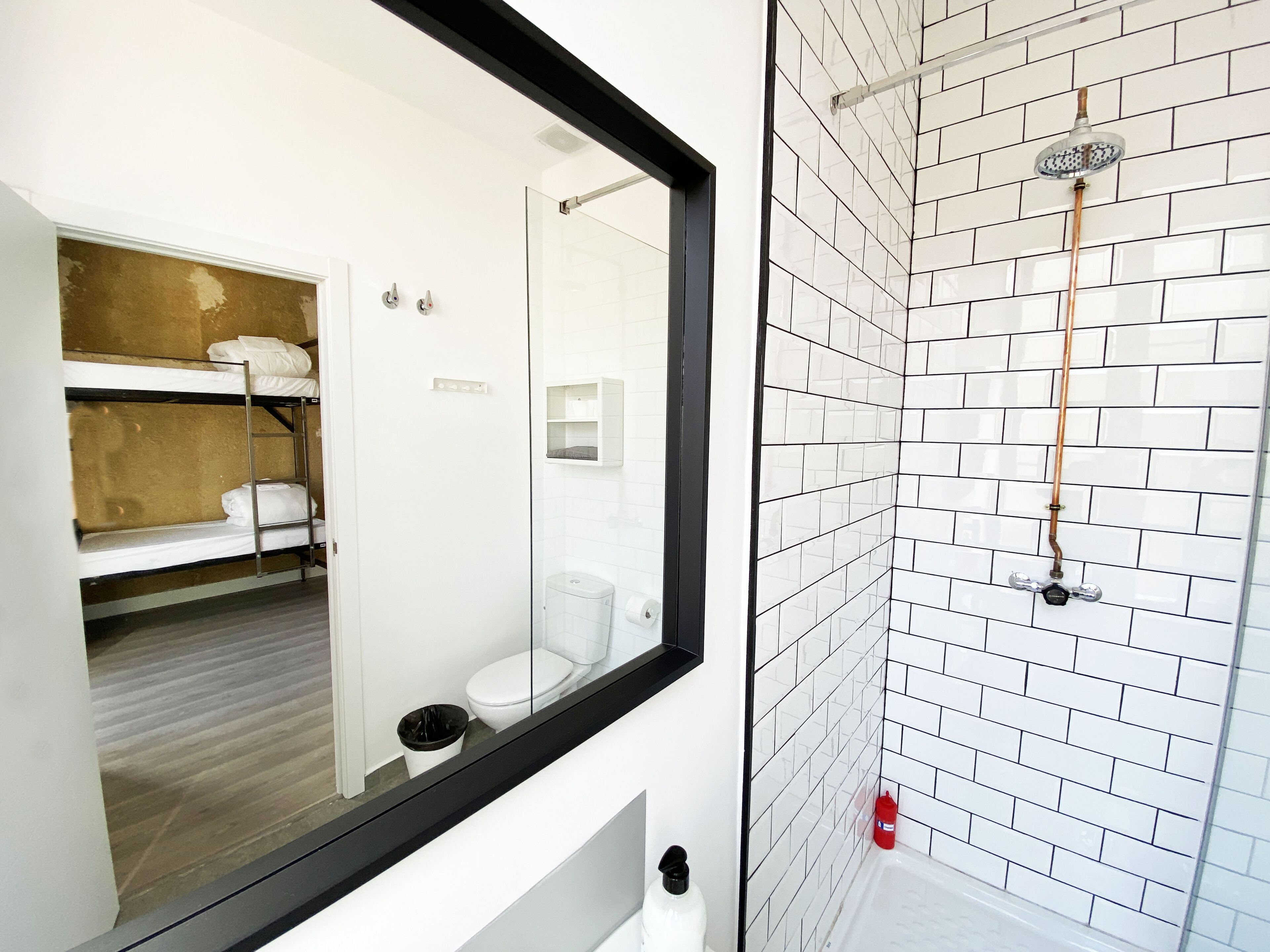 Ba ño con ducha, inodoro y zona con literas.