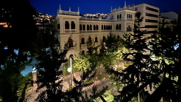 A historic building with multiple arches and a balcony, surrounded by trees and modern buildings. - ECO Hostel (Granada)
