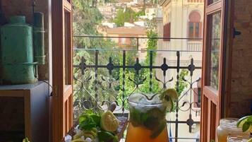 Uma varanda com vista para a paisagem urbana, com uma mesa, bebidas e um frasco decorativo.