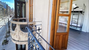 A balcony with a wrought iron railing, a wooden door, and a window with a view of the street below. - ECO Hostel (Granada)