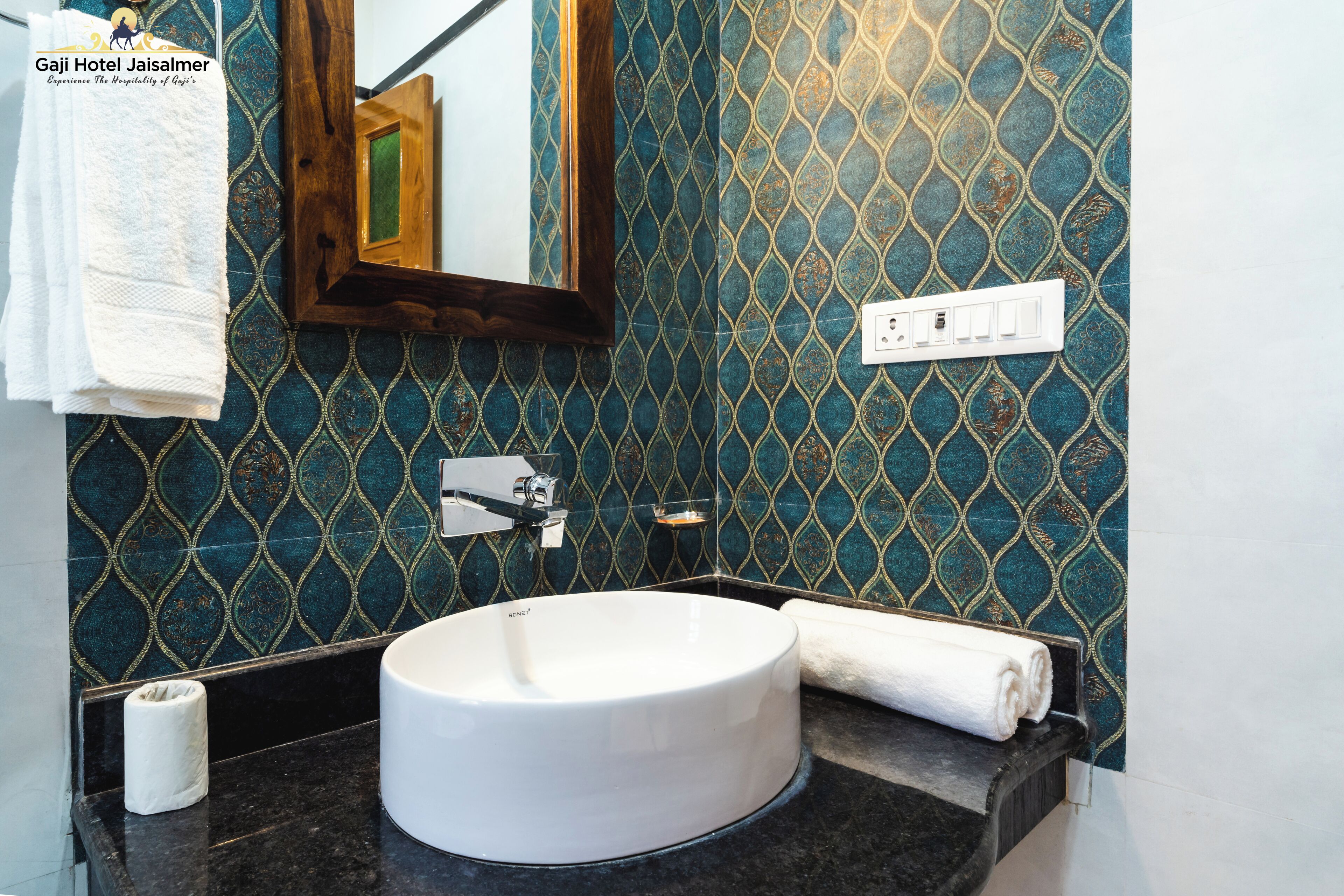 Un baño con un lavamanos blanco, un espejo y una pared azul con diseño.