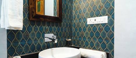 Un baño con un lavamanos blanco, un espejo y una pared azul con diseño.