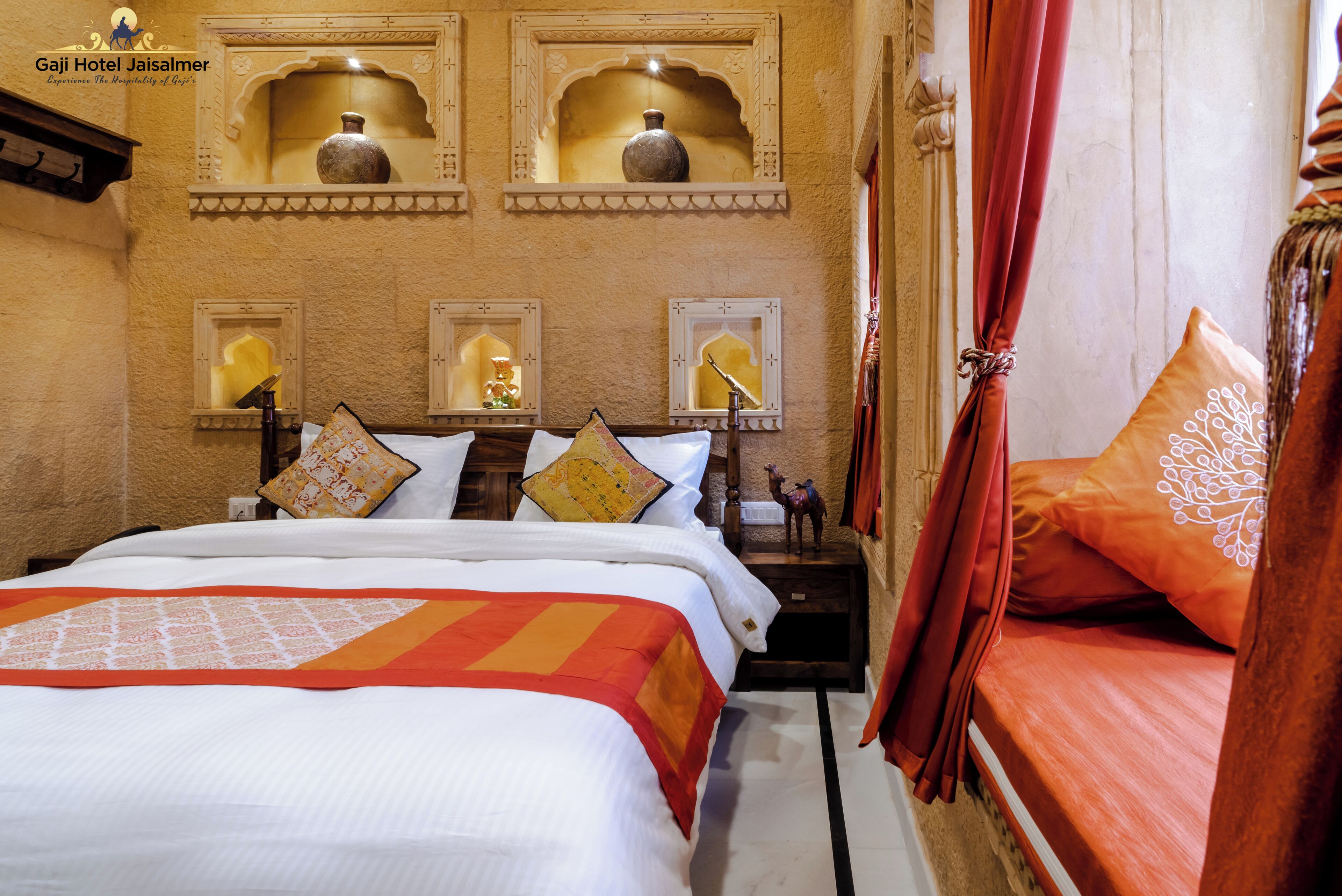 A hotel room with a bed, decorative pillows, a nightstand, and wall-mounted shelves with vases.