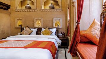 A hotel room with a bed, decorative pillows, a nightstand, and wall-mounted shelves with vases.